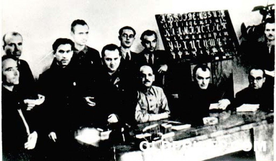 Членовите на првата јазична комисија: (седат) Ристо Проданов, Ѓорѓи Киселинов и Ѓорѓи Шоптрајанов, (стојат, прв ред) Васил Иљоски, Крум Тошев и Венко Марковски, (втор ред) Христо Зографов, Даре Џамбаз, Мирко Павловски, Михајло Петрушевски и најдесно Јован Костовски.